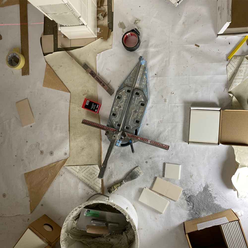Værktøj og hvide fliser fra Byggfabriken under renovering og forberedelse til lægning