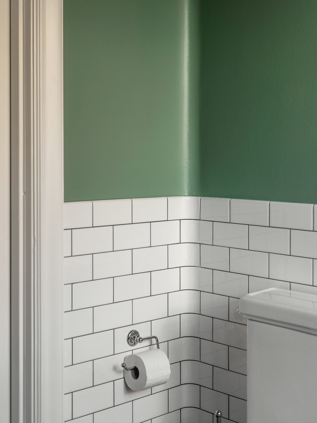 Badeværelseshjørne med grøn væg, hvide fliser og toiletrulleholder Badeværelseshjørne med grøn væg, hvide fliser og toiletrulleholder