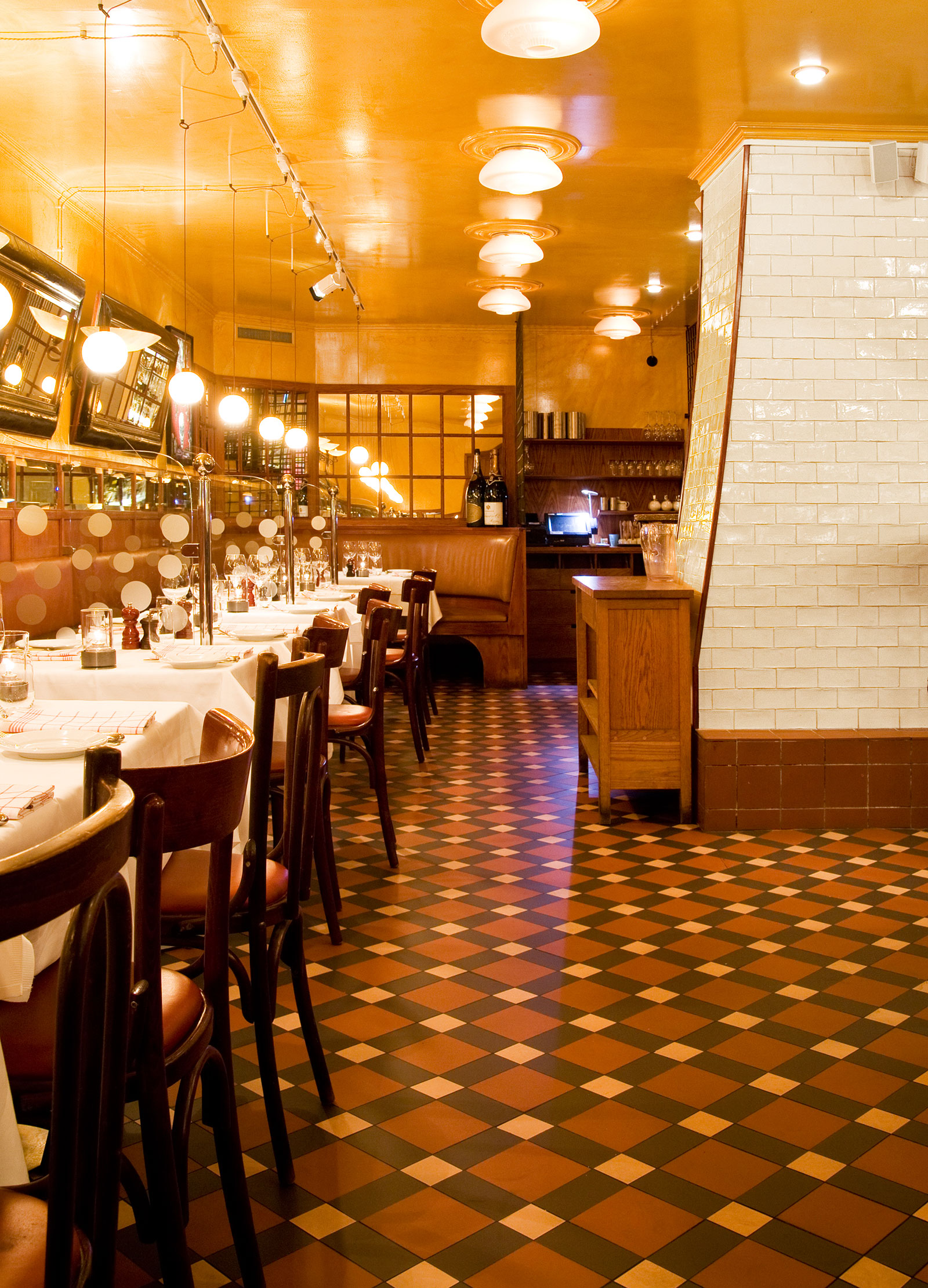 Restaurantafdeling med borde med hvide duge og tr&aelig;stole p&aring; klinkegulv af Victorian Floor Tiles