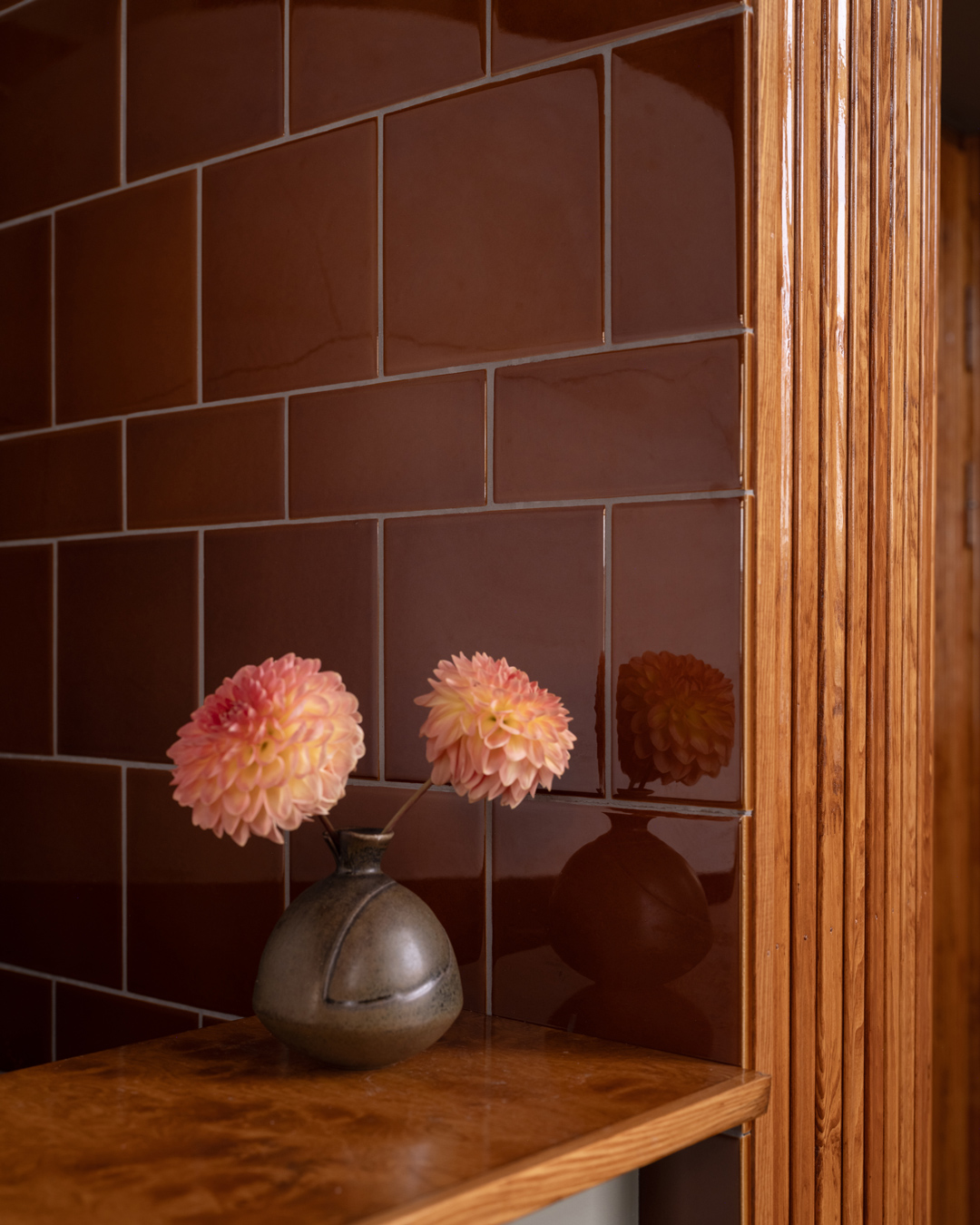 Væg med H&E Smith fliser i Victorian Brown og bardisk med vase og dahliaer